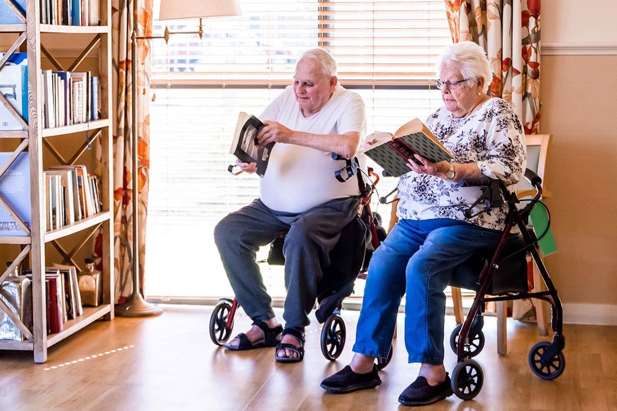 an elderly man and woman reading beside a window